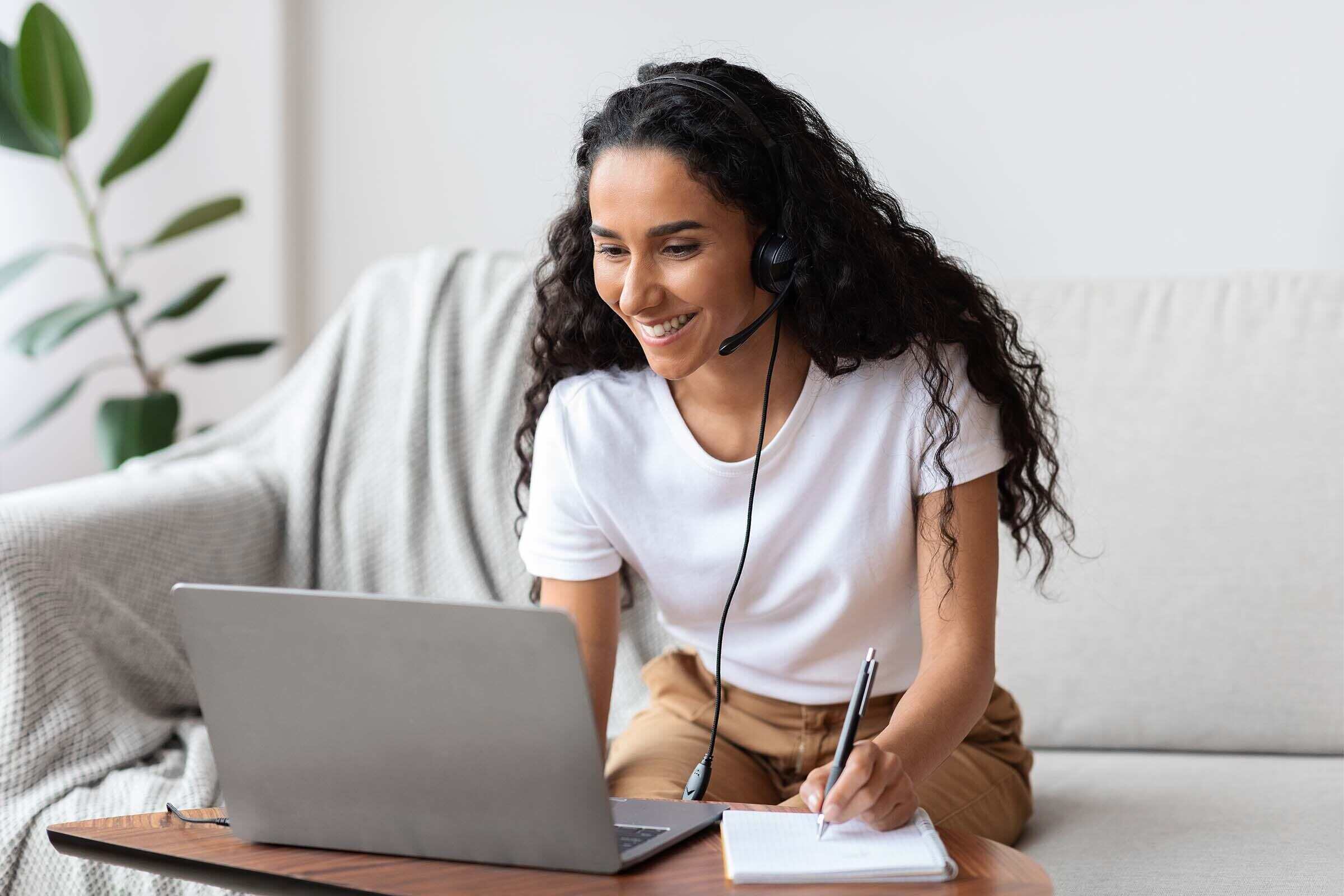 Joyful young woman studying online, using laptop at home